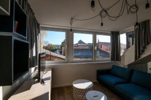 a living room with a blue couch and two windows at Smartflat & New apartment city center in Kaunas