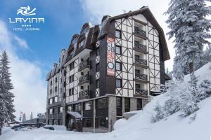 a building with snow on the ground in front of it at Hotel Lavina in Jahorina