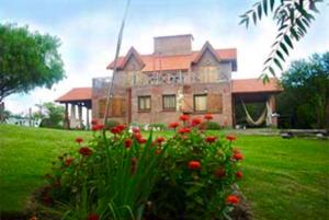 een groot huis met rode bloemen ervoor bij Chalets Andalgala in Merlo