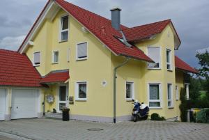 ein gelbes Haus mit einem Motorrad, das davor geparkt ist in der Unterkunft Haus Mantai in Freudenstadt
