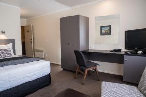 um quarto com uma cama e uma secretária com um computador em West Plaza Hotel em Wellington
