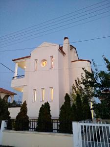a white house with a clock in the window at Prime Luxury Villa beach front in Nea Vrasna