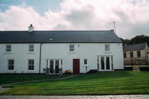 a white house with a lawn in front of it at Foyle Cottage in Strabane