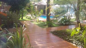a wooden walkway in a yard with a pool at Casa da Arvore Apartamentos Pousada in Arraial d'Ajuda