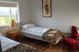 a bedroom with two beds and a chair and a window at Midhop guesthouse in Þingeyrar