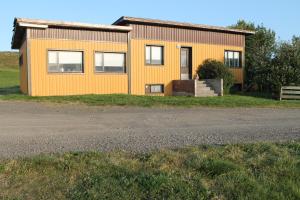 a yellow house on the side of a road at Midhop guesthouse in Þingeyrar