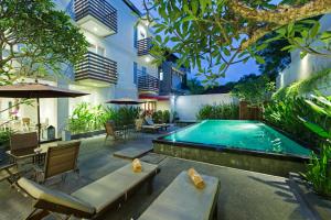 an outdoor pool with tables and chairs and a hotel at The Rinaya Canggu by ecommerceloka in Canggu