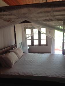 1 dormitorio con 1 cama con dosel y 2 ventanas en Jayanika home stay, en Tangalle