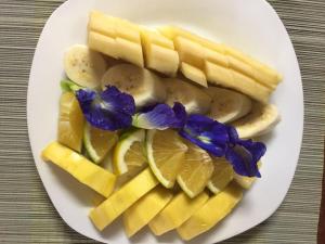 a plate of fruit and vegetables with purple flowers on it at Ning Ning Guesthouse in Ban Ngoy-Nua