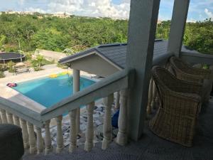 a balcony with a swimming pool and two chairs at Sagusta Gardens PLS in Providenciales