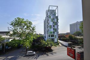 a white car parked in front of a tall building at Whiz Hotel Pemuda Semarang in Semarang