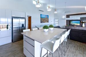 a kitchen with a large kitchen island with white chairs at Casuarina Cove Apartments in Hamilton Island