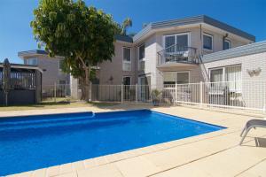 a house with a swimming pool in front of a house at The Sands Holiday Apartments in Merimbula