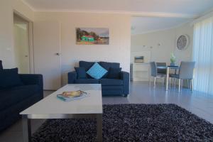 a living room with a blue couch and a table at The Sands Holiday Apartments in Merimbula