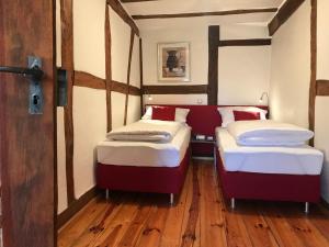 two beds in a small room with wooden floors at Boarding House Obernburg in Obernburg am Main