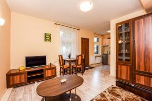 a living room with a table and a television at Apartamentai Pluke - Biliūno in Palanga