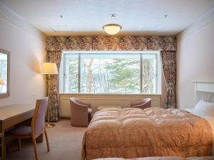 a bedroom with a bed and a desk and a window at Urabandai Lake Resort in Kitashiobara