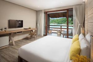 a bedroom with a bed and a desk and a television at Beach Club by Haadtien in Koh Tao