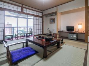 uma sala de estar com uma mesa e uma varanda em Riverside Hotel Shoei em Kochi