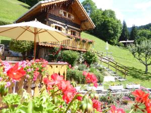 a house with an umbrella and flowers in front of it at Chalet Fleur des Neiges in Saint-Jean-dʼAulps