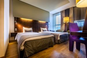 ein Hotelzimmer mit zwei Betten und einem Schreibtisch in der Unterkunft Hotel Artemis Amsterdam in Amsterdam