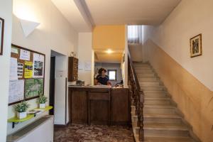 une femme debout à un comptoir dans un couloir avec escalier dans l'établissement Albergo Vecchio Forno, à Spolète