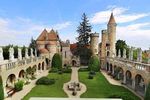 a large castle with a yard with grass and trees at Korona Apartman Székesfehérvár in Székesfehérvár