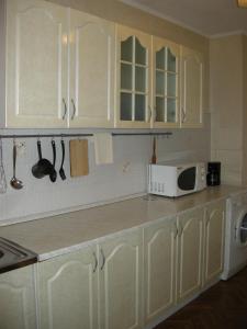 La cuisine est équipée de placards blancs et d'un four micro-ondes blanc. dans l'établissement Apartament in chirie, à Chişinău