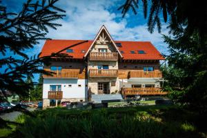 una grande casa in legno con tetto arancione di Pensiunea Colt de Rai a Beliş