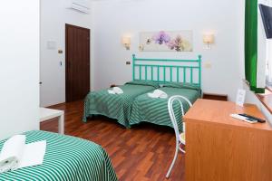 um quarto com 2 camas, uma secretária e uma mesa em Affittacamere Orchidea em Ancona