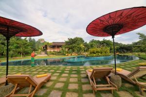 ein Resort mit einem Pool, 2 Stühlen und Sonnenschirmen in der Unterkunft Popa Garden Resort in Popaywa