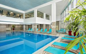 Ramada Olivie Nazareth في الناصرة: مسبح في فندق والكراسي الزرقاء