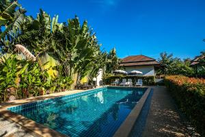 a swimming pool in front of a house at Himaphan Boutique Resort - SHA EXTRA PLUS in Nai Yang Beach