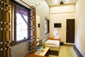 ムンバイにあるウェルカム ゲストハウスのベッドと窓が備わる小さな客室です。