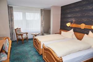 um quarto de hotel com duas camas e uma cadeira em Hotel Odenwaldblick em Rödermark