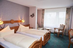 um quarto de hotel com duas camas e uma cadeira em Hotel Odenwaldblick em Rödermark