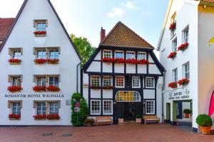 um edifício preto e branco com flores vermelhas em Romantik Hotel Walhalla em Osnabrück