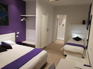 ヴェローナにあるSuite Color Veronaの紫の壁のホテルルーム(ベッド2台付)