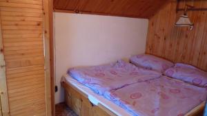 Cama pequeña en habitación de madera con en Chata Renďo, en Kokava na Rimavica