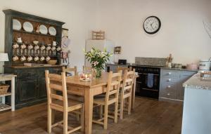 a kitchen with a wooden table and chairs and a clock at Burrows in Venn Ottery