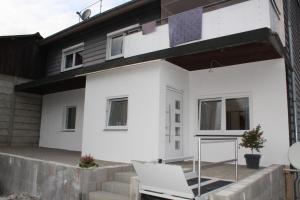 une maison blanche avec une chaise en face dans l'établissement Ferienwohnung Albblick 1 Münsingen, à Münsingen