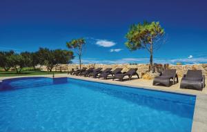 a swimming pool with chaises and chairs in a resort at Villa Dabo in Novalja