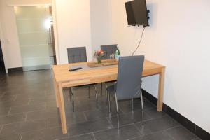 einen Holztisch mit Stühlen und einen TV an der Wand in der Unterkunft Ferienwohnung Albblick 1 Münsingen in Münsingen