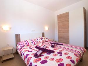 a bedroom with a bed with purple and pink sheets at Apartments Biljana 1480 in Ližnjan