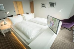 a hotel room with a white bed and a desk at Altera Hotel in Oldenburg