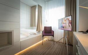 a room with a bed and a chair and a tv at Altera Hotel in Oldenburg