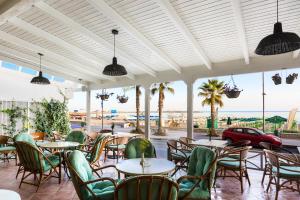 レティムノ・タウンにあるPoseidon Hotelのテーブルと椅子が備わり、海の景色を望むレストラン