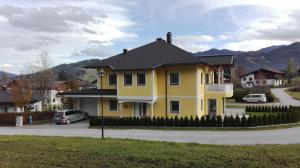 a yellow house with a black roof on a street at Appartement Grießenkareck in Flachau