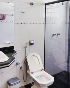 a bathroom with a shower with a toilet and a sink at Suítes La Cabana in Capitólio