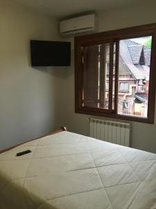 Un dormitorio con una gran cama blanca y una ventana en Res. Alcides Balzaretti, en Gramado